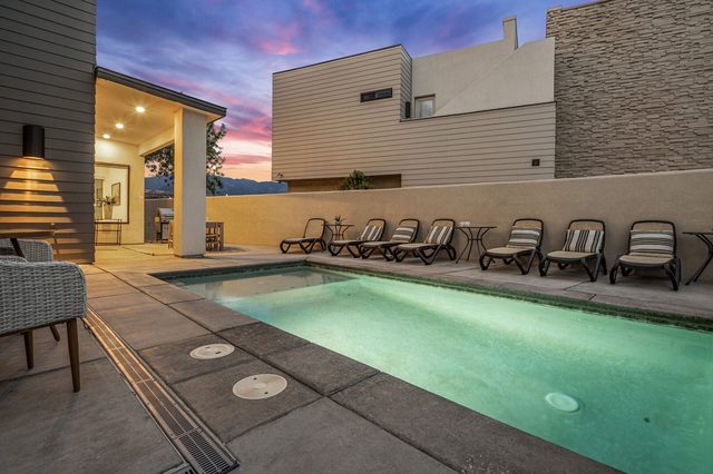 Private pool glowing at dusk beside the covered patio