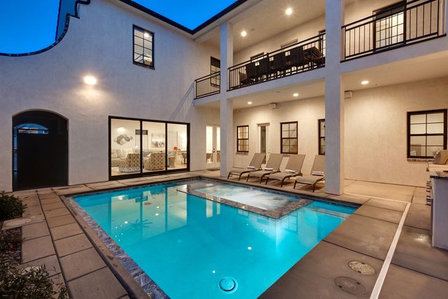 Courtyard pool and spa beneath second-floor balcony at dusk