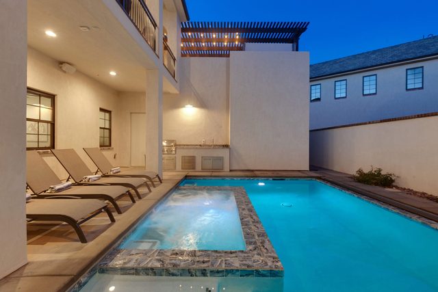 Private spa spilling into the pool beside loungers at dusk