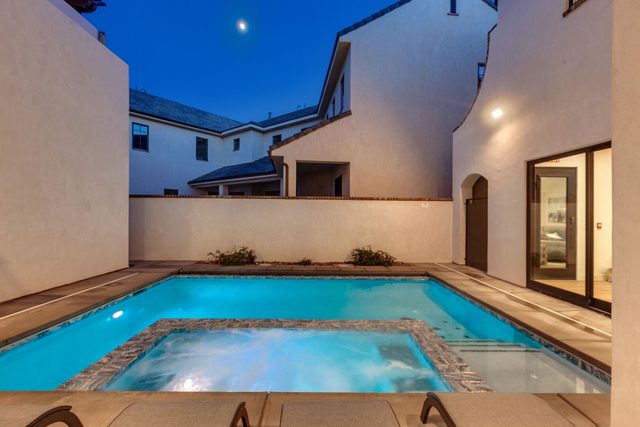 Private pool and spa glowing at night beside the house