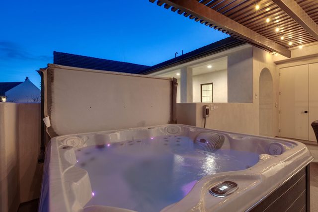 Rooftop hot tub with lights under the pergola at dusk