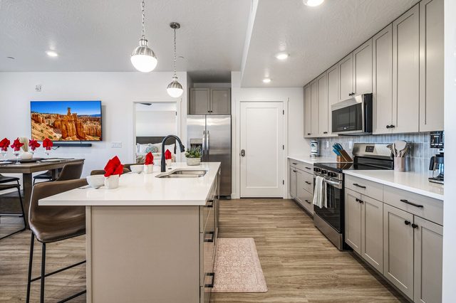 Kitchen with gray cabinets, stainless appliances and island seating