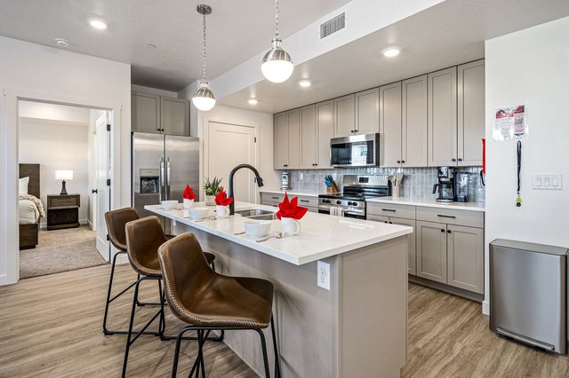 Kitchen island with three leather bar stools and pendant lights