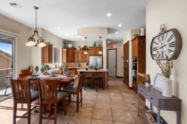 Dining table and kitchen with wood cabinets and tile floors