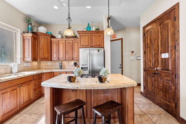 Kitchen island with bar stools, granite counters and stainless refrigerator