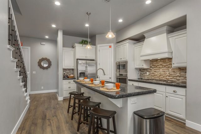White kitchen with granite island seating beside the staircase