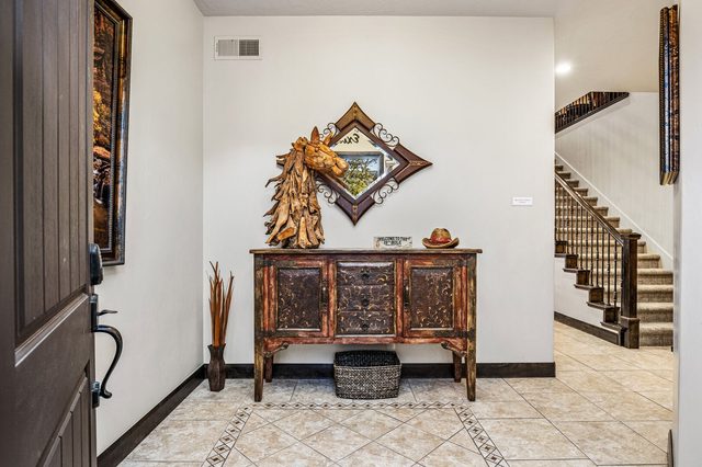 Tiled entry with carved console table and staircase