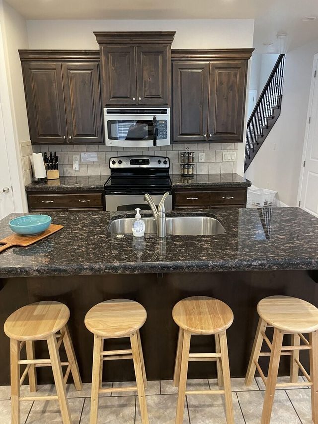 Kitchen island with four wooden stools and stainless appliances