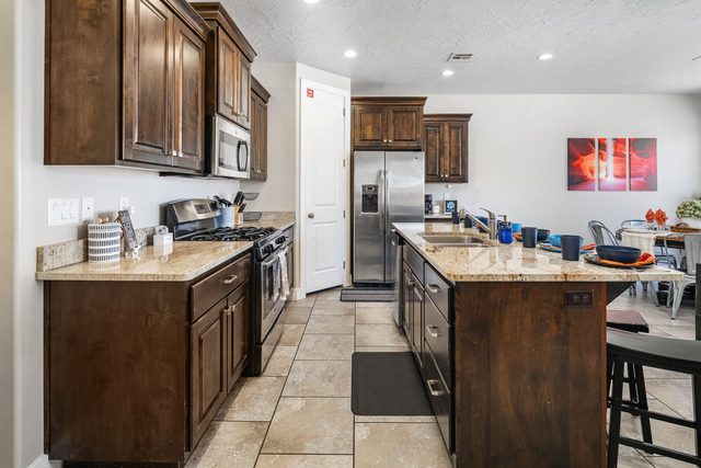 Kitchen with gas range, stainless fridge and granite island