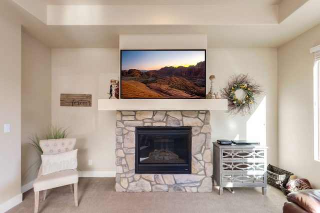 Stone gas fireplace with mounted TV and accent chair