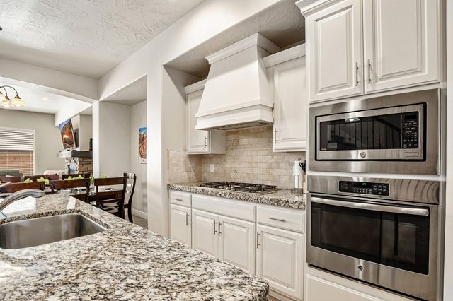 Kitchen with wall oven, microwave and gas cooktop under range hood