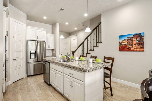 Kitchen with stainless refrigerator, white cabinets and island
