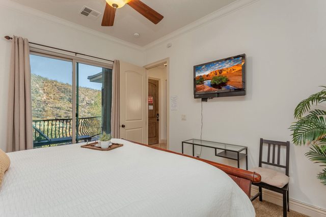 King master suite with wall TV and sliding door to balcony