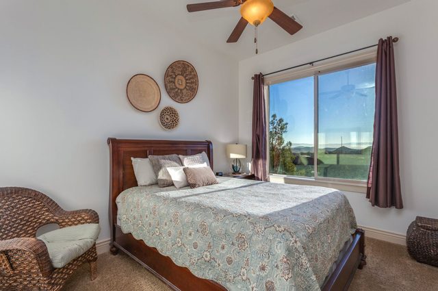 Second bedroom with queen bed, wicker chair and window view