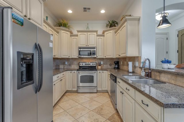 Kitchen with cream cabinets, granite counters and stainless appliances