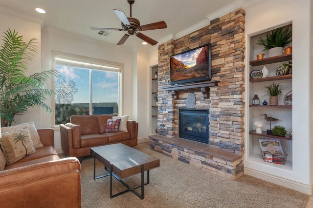 Living room with stacked stone fireplace, TV and leather sofas