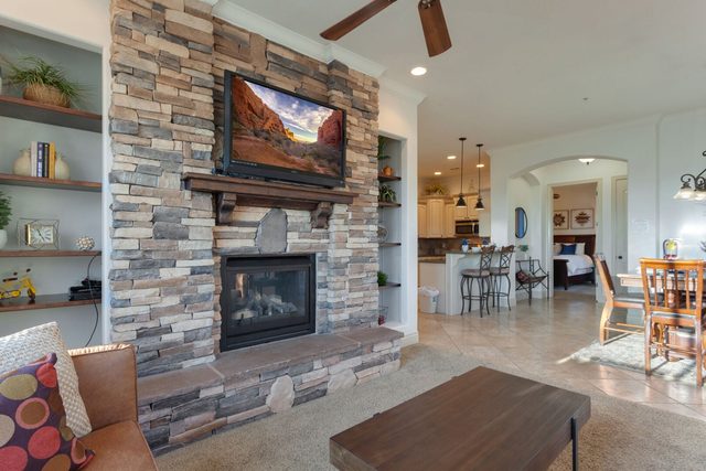 Open living area with stone fireplace looking toward kitchen and dining