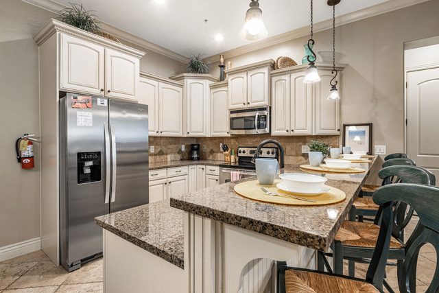 Kitchen with granite breakfast bar, stainless fridge and cream cabinets