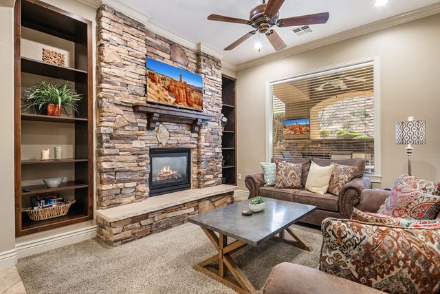 Living room with stacked stone gas fireplace, TV and built-in shelves