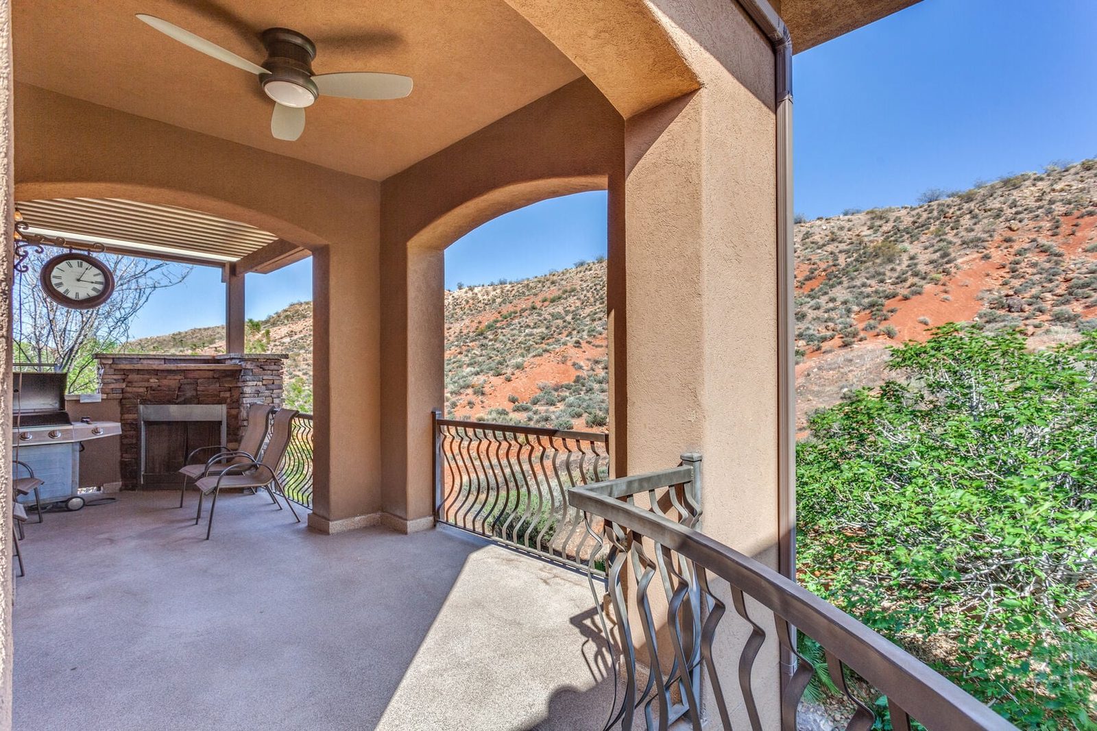 Covered balcony with outdoor fireplace, grill and red rock hillside view