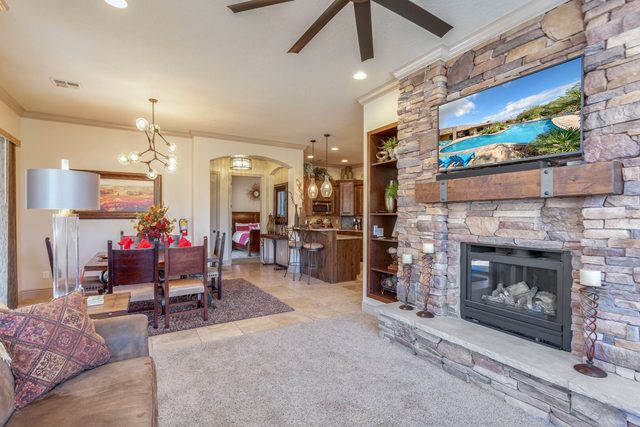 Living room with stone fireplace and TV opening to dining area