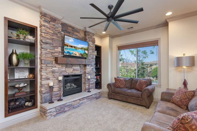 Living room with stacked stone fireplace, built-in shelves and TV