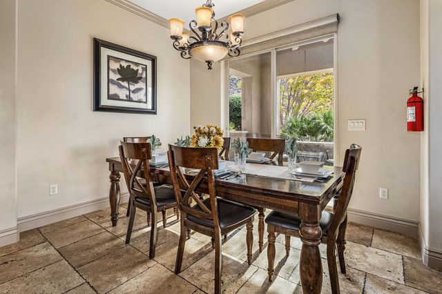 Dining table with chandelier next to a garden window