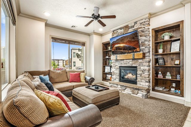 Living room with stone fireplace, built-in shelves and sectional sofa