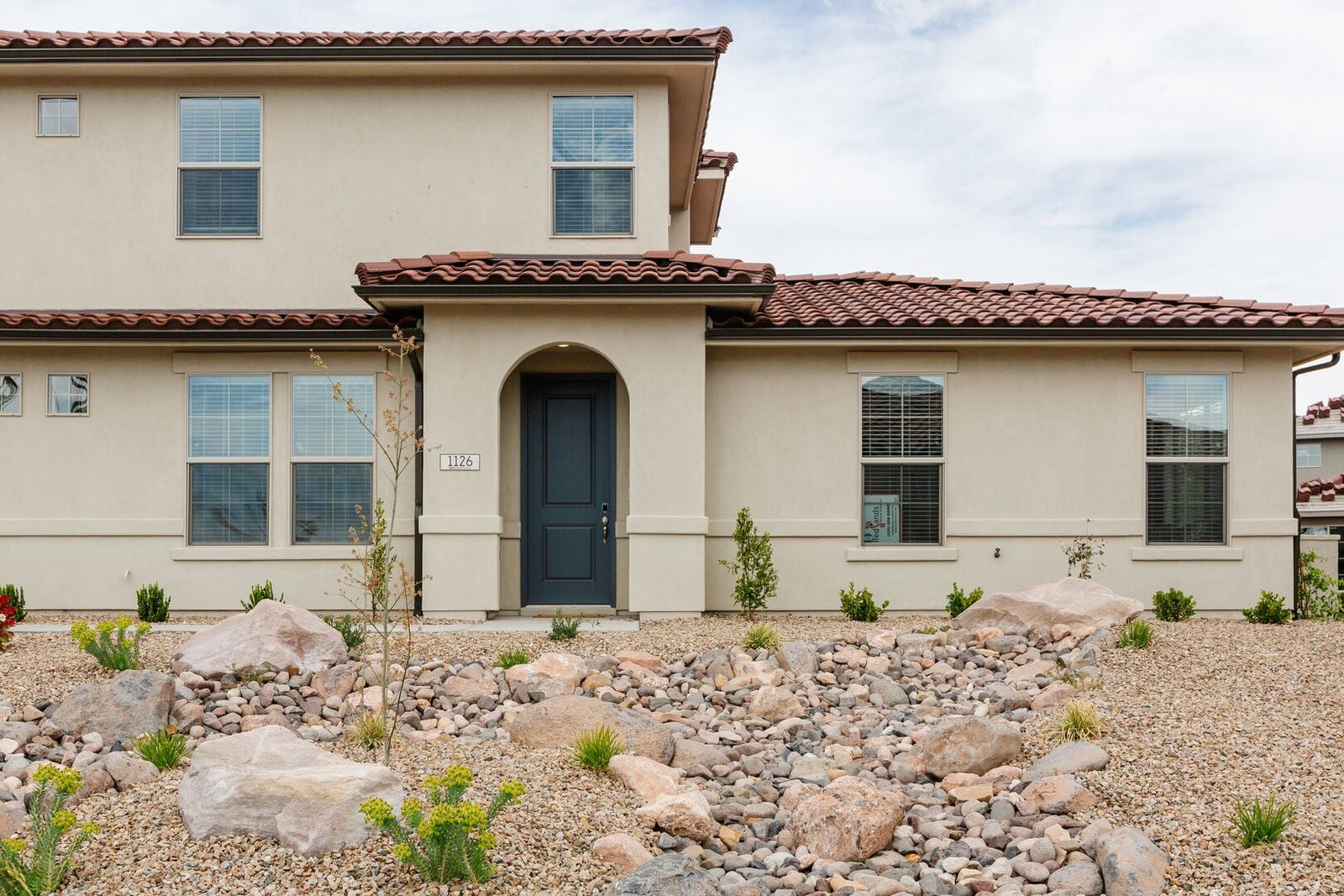 Front exterior of Escondido 1126 townhome with tile roof and desert landscaping