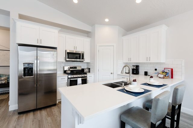 White kitchen with quartz island, pantry door and stainless appliances