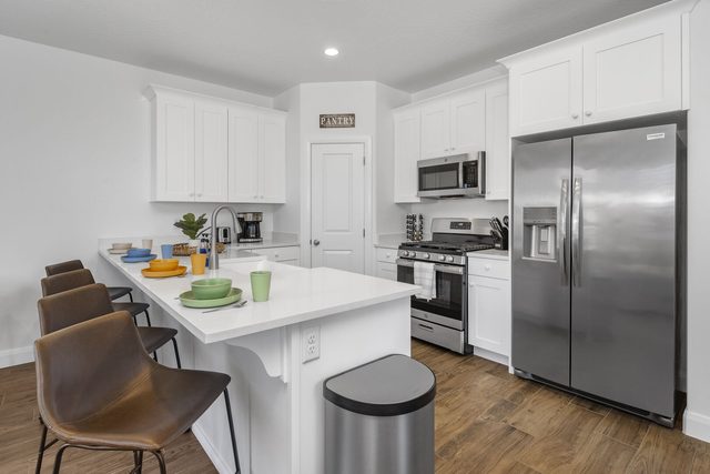 White kitchen with island seating and stainless fridge at Escondido 1145