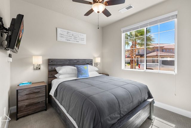 Downstairs queen bedroom with gray bedding and wall TV