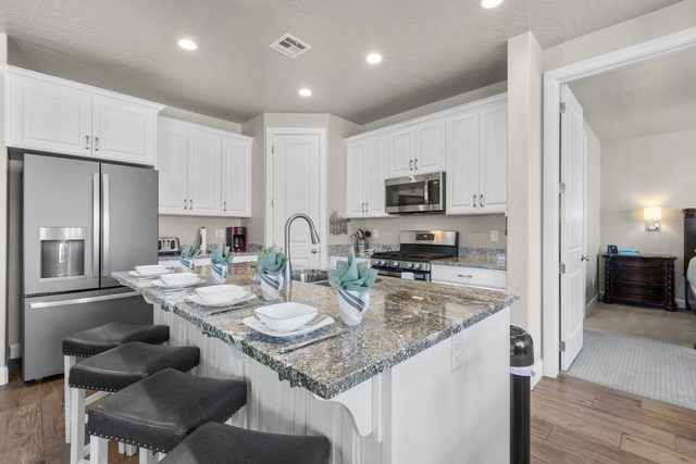 Kitchen with stainless refrigerator, gas range and island seating