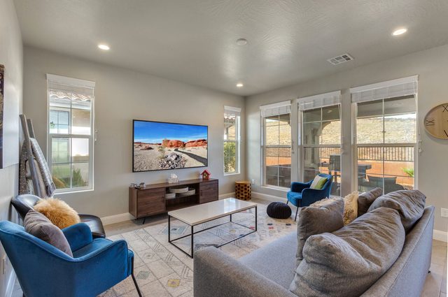 Great room with sofa, blue accent chairs and wall TV