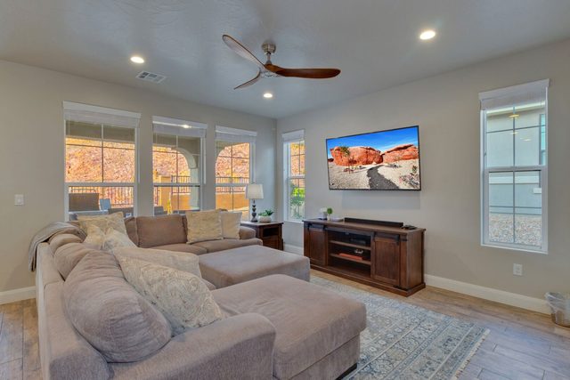Living room with sectional sofa, ceiling fan and wall-mounted TV
