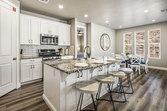 Kitchen with granite island seating and white cabinets in unit 2355