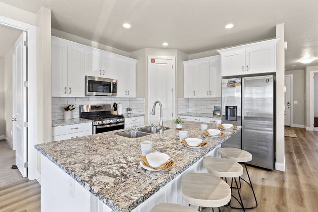 White kitchen with granite island and four bar stools