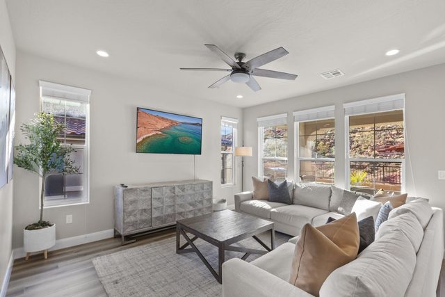 Great room with white sectional, coffee table and wall-mounted TV