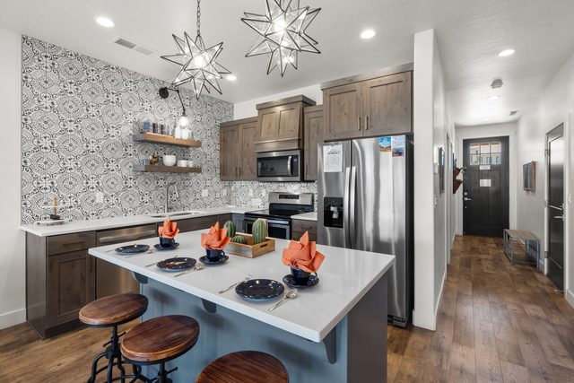 Home 523 kitchen with bar stools, stainless fridge and patterned backsplash
