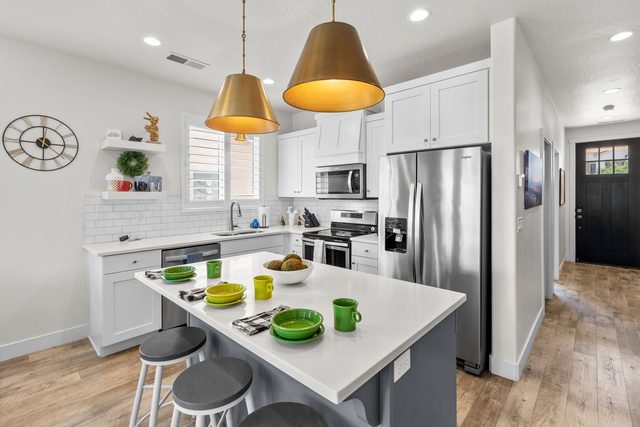 Home 529 white kitchen with island, bar stools and brass pendants