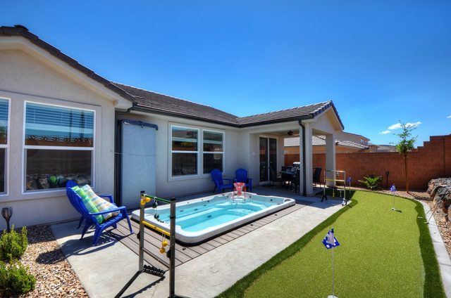 Private swim spa, Adirondack chairs and putting green in the backyard