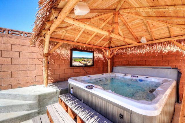Hot tub under the tiki hut with a mounted outdoor TV