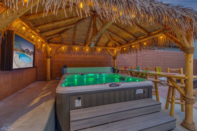 Hot tub lit green under string lights in the tiki hut