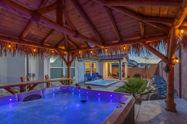 Hot tub glowing under the tiki hut with swim spa beyond