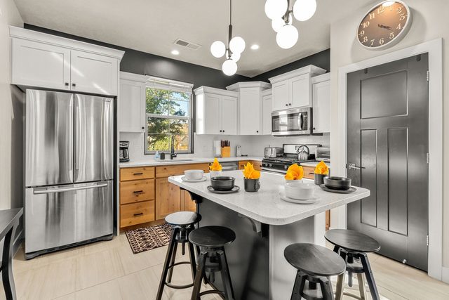 Kitchen island with stools, stainless fridge and white cabinets