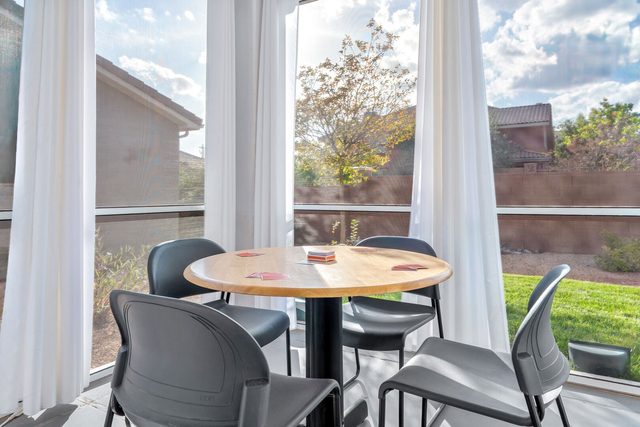 Sun room game table beside windows overlooking the lawn