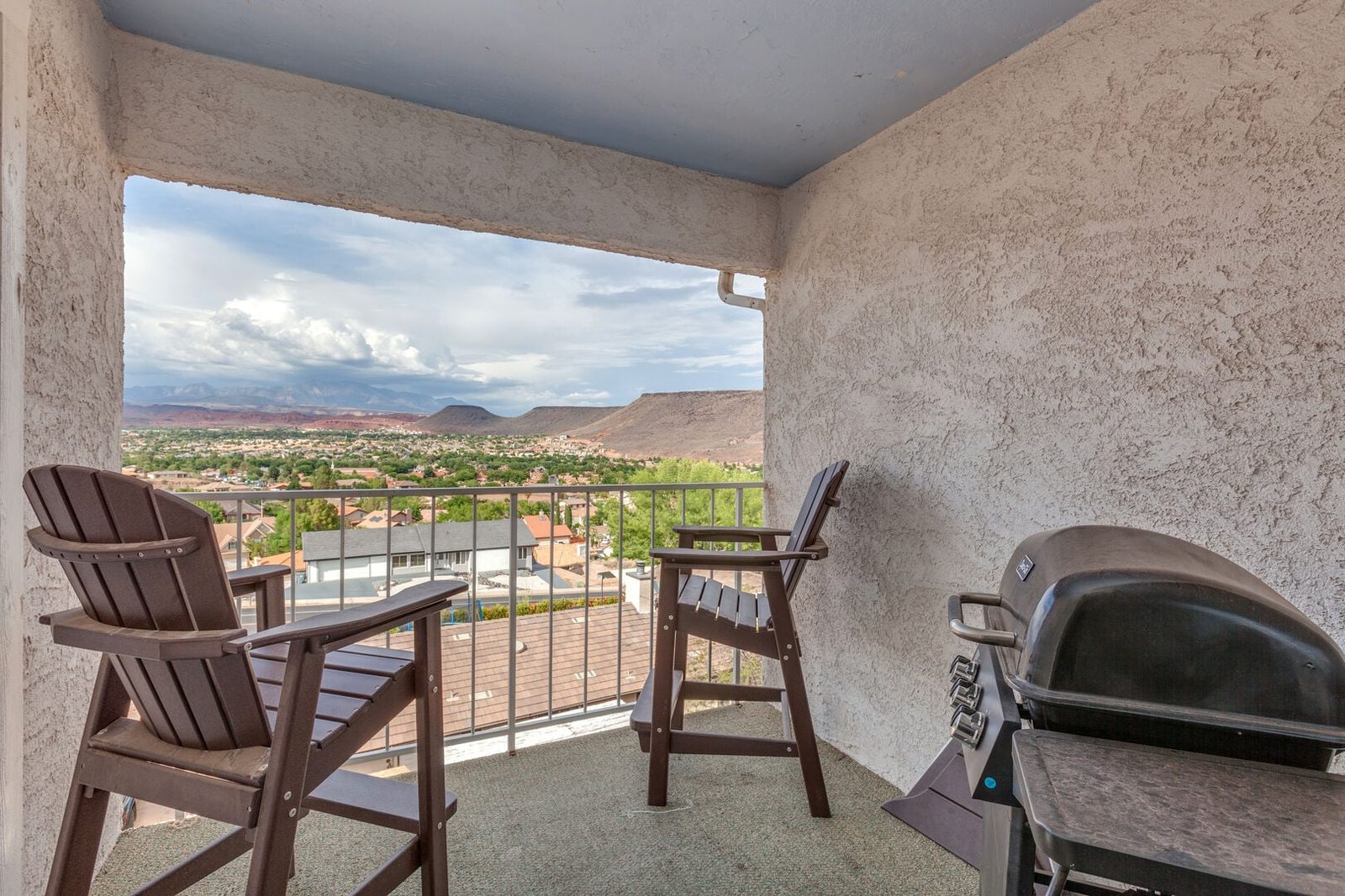 Balcony with two tall chairs, grill and valley views