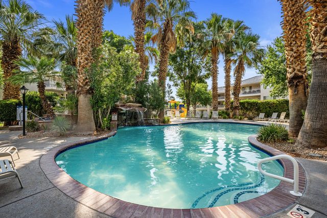 Palm-shaded community pool with rock waterfall at Las Palmas resort