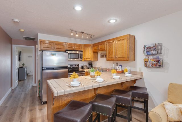 Kitchen breakfast bar with four stools and stainless refrigerator
