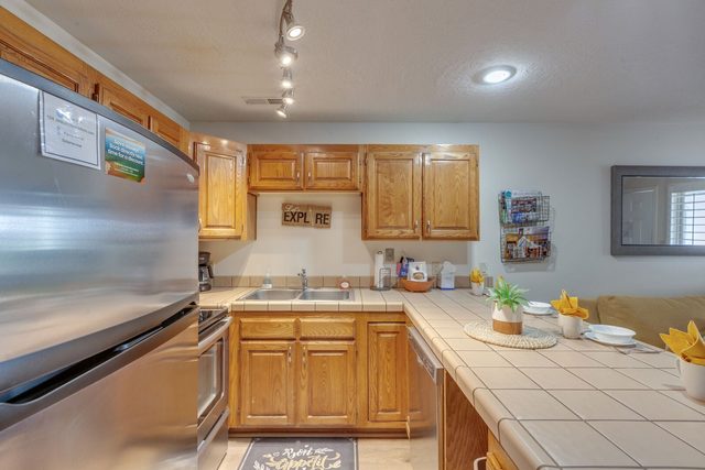 Kitchen with oak cabinets, tile counters and stainless appliances
